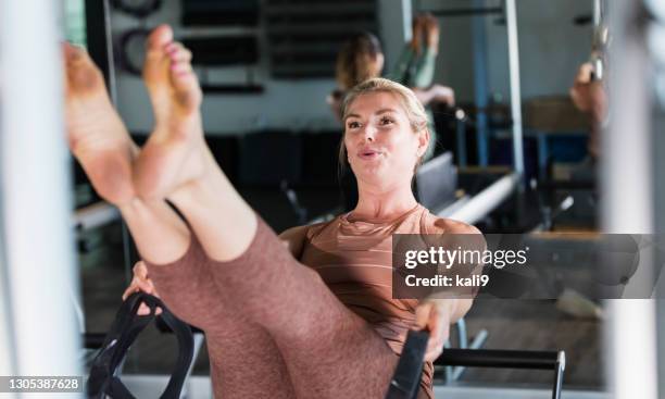 mid adult woman working out in pilates studio - pilates gerät stock-fotos und bilder