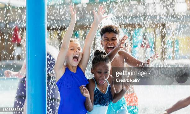 gruppe von kindern, die in einem wasserpark spielen - girls and boys playing in waterpark stock-fotos und bilder