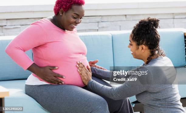 pregnant woman with doula touching baby bump - doula stock pictures, royalty-free photos & images