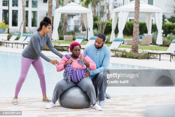 doula helping pregnant couple, using fitness ball - fitness ball imagens e fotografias de stock