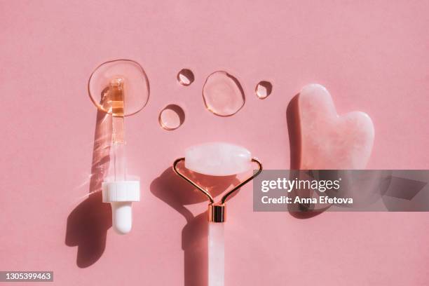 quartz massager guasha, quartz face roller, pipette and hyaluronan acid drops on pink background in knolling style. trendy products of the year. health and wellness concept - spooning stock pictures, royalty-free photos & images