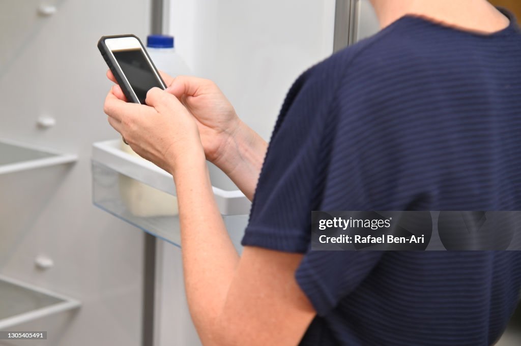 Woman adding grocery items to shopping list on mobile phone