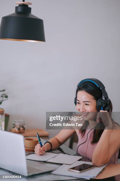 asian chinese beautiful woman smiling attending online class in the kitchen using laptop - laptop headset stock pictures, royalty-free photos & images