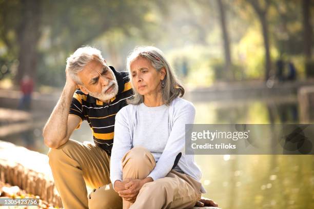 senior mann consoling seine wütende frau - sad old man stock-fotos und bilder