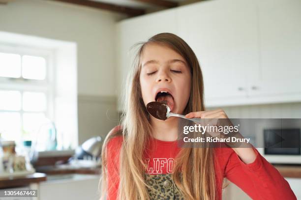 a young girl licking a chocolate covered spoon - girl baking stock pictures, royalty-free photos & images