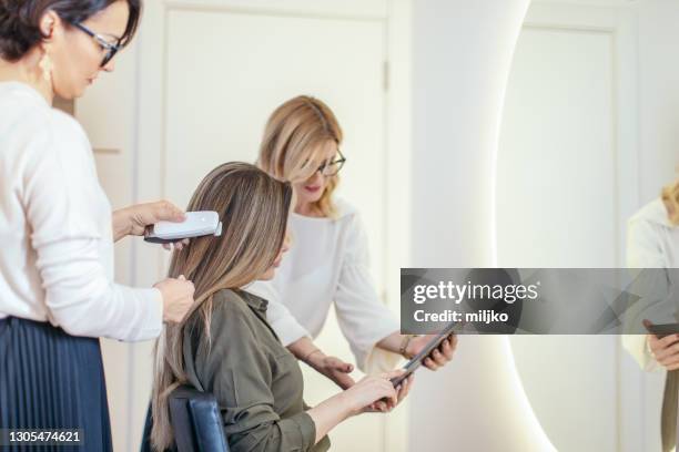 woman at the hair salon having consultations before the treatment - examining hair stock pictures, royalty-free photos & images