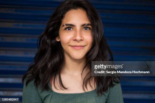 young latino woman smiling at the camera with a blue background in mexico city, mexico - cute teens stock pictures, royalty-free photos & images