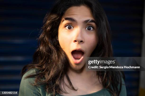 young latino woman with a blue background looks surprised - mexico city, mexico - woman awe stock pictures, royalty-free photos & images