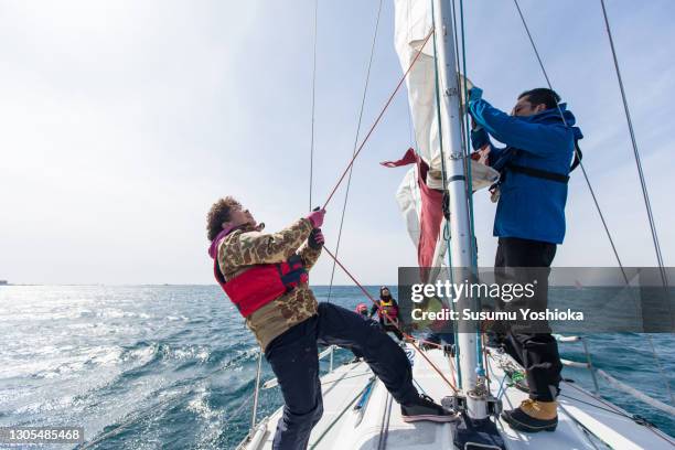 a group of middle-aged and older adults enjoying a winter weekend sailing in the ocean. - sail stock pictures, royalty-free photos & images