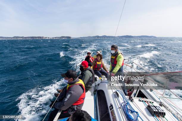 a group of middle-aged and older adults enjoying a winter weekend sailing in the ocean. - sailing club stock pictures, royalty-free photos & images