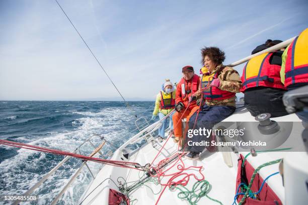 a group of middle-aged and older adults enjoying a winter weekend sailing in the ocean. - scheepsonderdeel stockfoto's en -beelden