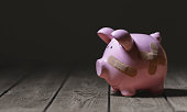 Broken piggy bank with band aid bandage or plaster finance background