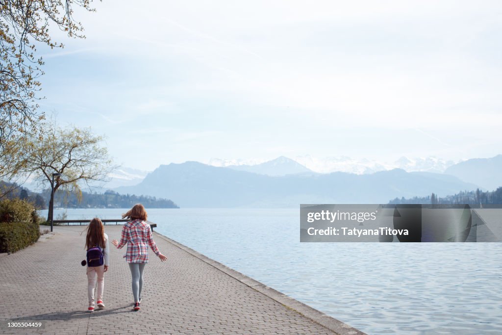 Two girls are walking along the shore of lake Lucerne