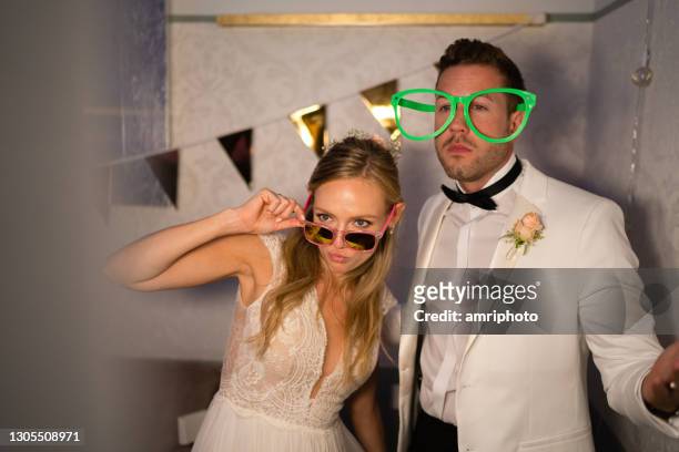 casal recém-casado se divertindo em frente ao estande phto em sua noite de festa de festa de casamento - photomaton - fotografias e filmes do acervo