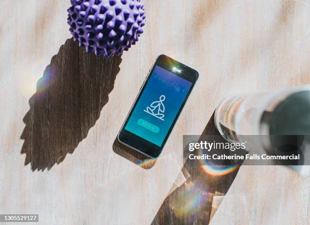 mobile phone displaying a meditation app, beside a water bottle and a spiked massage ball - yoga ball work 個照片及圖片檔