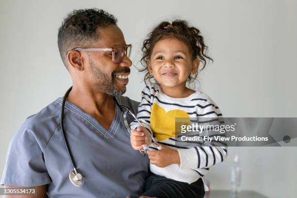 portret van een mannelijke verpleegster die een leuk meisje houdt - cute nurses stockfoto's en -beelden