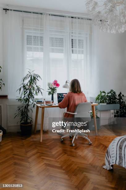 arbeiten von zu hause: rückansicht einer seniorin mit ihrem laptop-computer von zu hause aus - die neue normalität stock-fotos und bilder