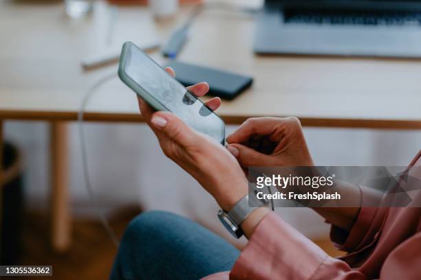hands of an anonymous woman connecting a power bank to her smartphone - network connection stock pictures, royalty-free photos & images
