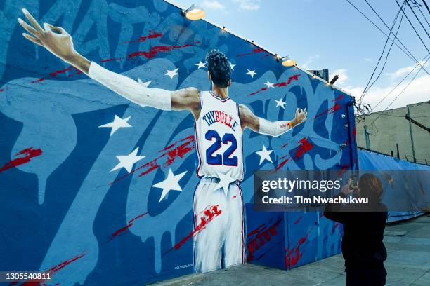 Passerby photographs a mural of Matisse Thybulle of the Philadelphia 76ers seen on the side of the Fishtown neighborhood bar Garage on March 04, 2021...