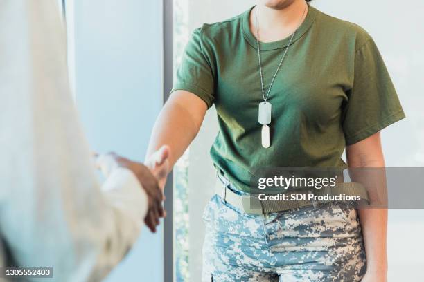 unrecognizable female soldier greets civilian - army civilian stock pictures, royalty-free photos & images