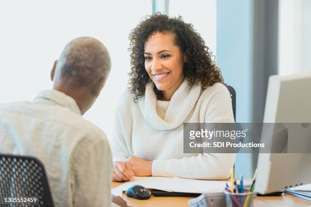 female banker smiles while listening to senior man - two bank managers talking stock pictures, royalty-free photos & images
