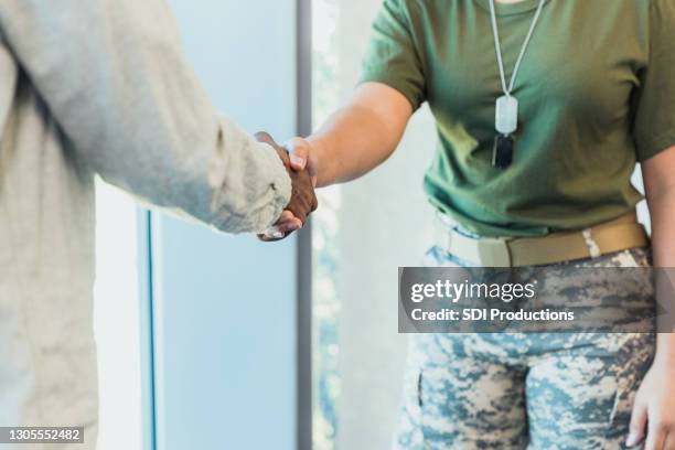 soldier shares firm handshake with unrecognizable man - army soldier male stock pictures, royalty-free photos & images