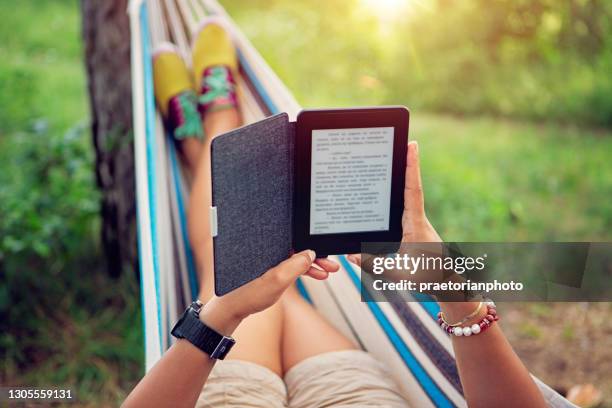 mujer está leyendo libro electrónico en una hamaca - lector de libros electrónicos fotografías e imágenes de stock