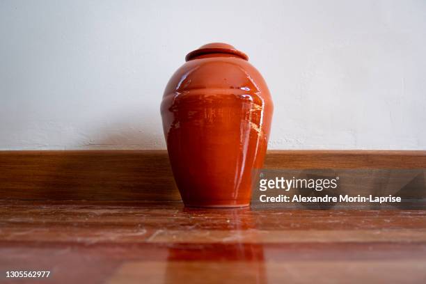 orange urn leaning against the white wall - grecian urns stock-fotos und bilder