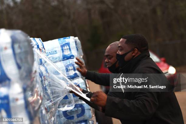 Derrick Kelly removes shrink wrap from a pallet of bottled water at a water distribution site in the parking lot of Forest Hill High School on March...