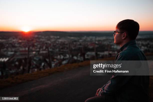 young man standing on hill top enjoying the sunset - metzingen stock pictures, royalty-free photos & images