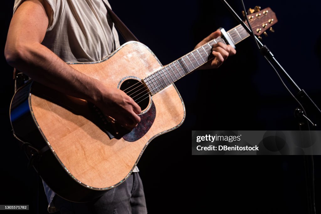 Guitarist - Singer playing the guitar during his concert