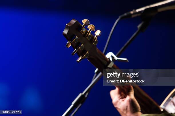 detail of a guitar neck held by a singing guitarist during a concert on a blue background - string instrument stock pictures, royalty-free photos & images