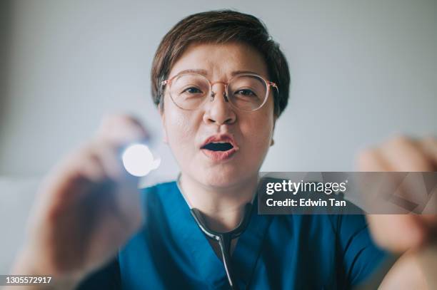 personal point of view asian chinese female doctor home visit using torch light checking on patient mouth - tongue depressor stock pictures, royalty-free photos & images