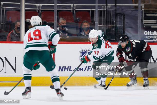 Brad Hunt of the Minnesota Wild skates with the puck ahead of Niklas Hjalmarsson of the Arizona Coyotes during the first period of the NHL game at...