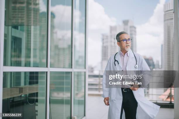 asian chinese male doctor walking towards his office - elderly chinese man stock pictures, royalty-free photos & images