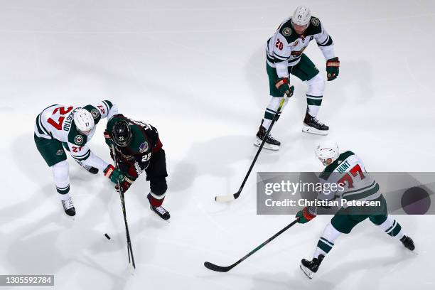 Johan Larsson of the Arizona Coyotes skates with the puck against Nick Bjugstad, Brad Hunt and Ryan Suter of the Minnesota Wild during the third...