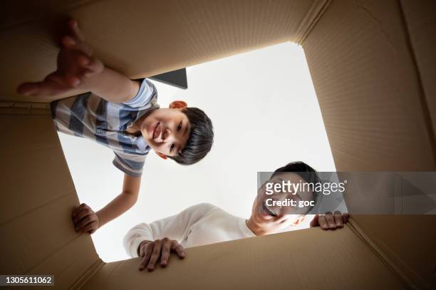 asian father and son unpacking and opening carton box delivered and purchased online, feeling surprise and excited while looking inside. - box in open stock pictures, royalty-free photos & images