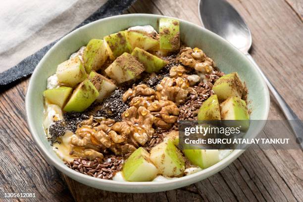 oatmeal yogurt bowl with green apples, flaxseed, chia seed, and walnuts - flax seed stock pictures, royalty-free photos & images
