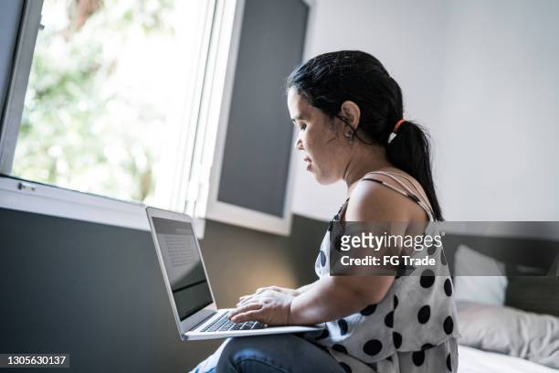 dwarfism woman using laptop on bed at home - little people stock pictures, royalty-free photos & images