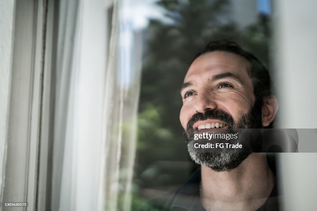 Homem maduro olhando pela janela em casa