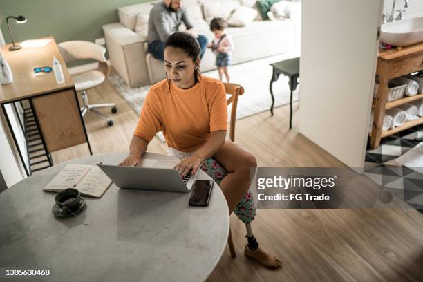 gehandicapte vrouw die laptop gebruikt die thuis werkt - disabilitycollection stockfoto's en -beelden
