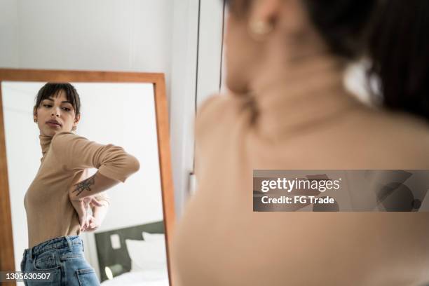 young woman getting dressed in front of a mirror at home - espelho imagens e fotografias de stock