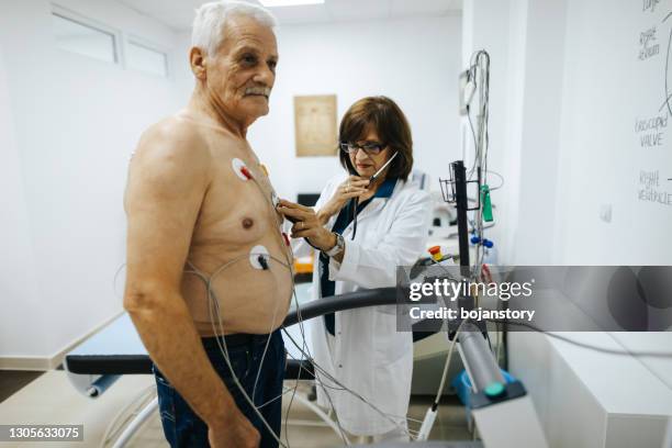 reife ärztin mit stethoskop auf senior männlichen patienten während herzstresstest auf laufband in kardiologische klinik - belastungsprobe stock-fotos und bilder