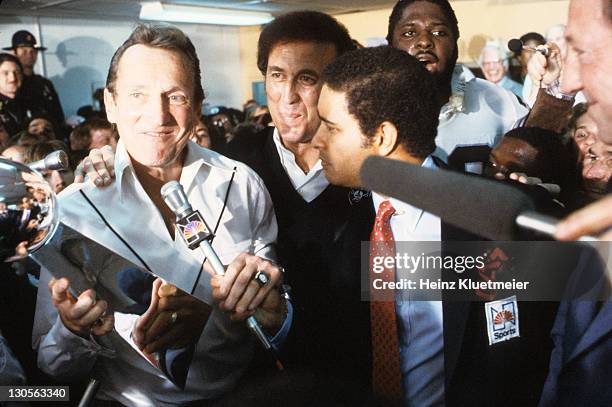 Super Bowl XV: Oakland Raiders general manager Al Davis victorious in locker room holding Lombardi trophy during interview with NBC Sports announcer...