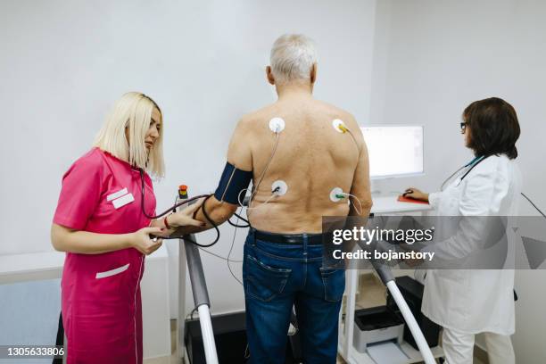 senior male patient having a cardiac stress test on a treadmill at clinic for cardiology - electrode stock pictures, royalty-free photos & images