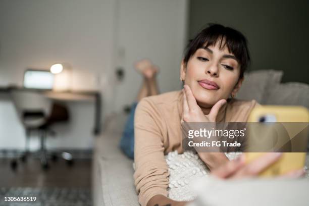 woman analyzing something on smartphone at home - video reviewed stock pictures, royalty-free photos & images