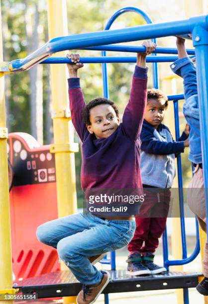 mixed race boy playing on playground monkey bars - monkey bars stock pictures, royalty-free photos & images