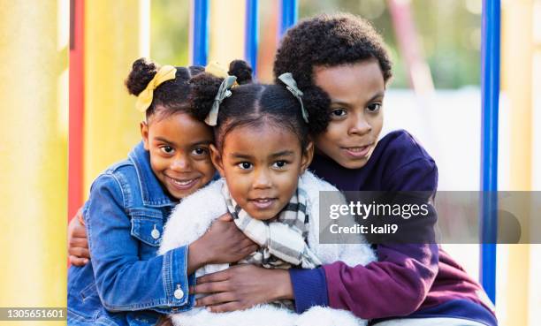 three young siblings hugging on playground - sister stock pictures, royalty-free photos & images