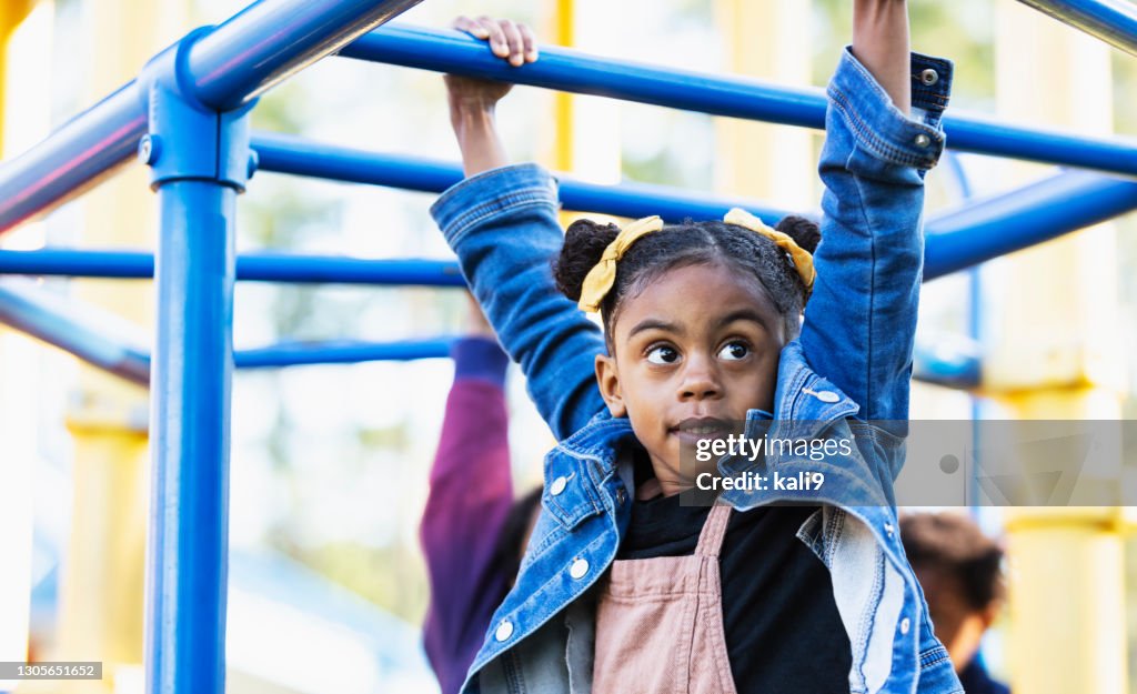 Mixed race girl playing on playground monkey bars