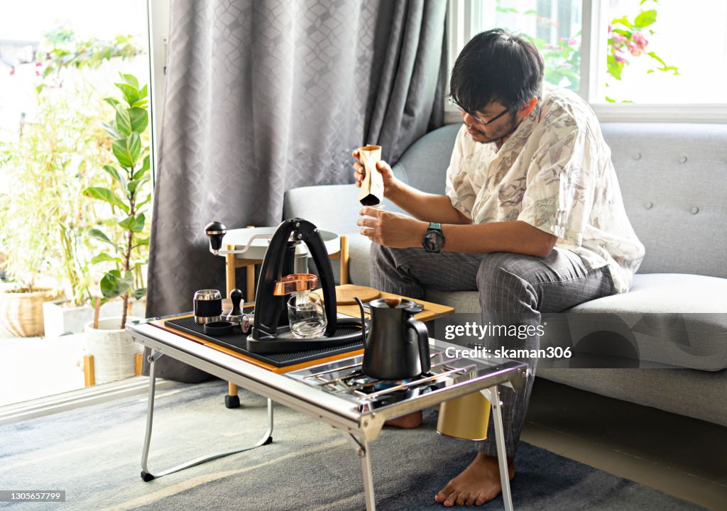 Wide agle of solo asian young man adult grinder coffee bean for brewing hot espresso daily life at home